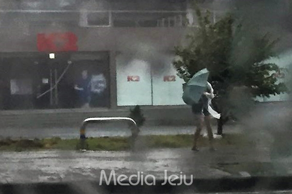 제19호 태풍 솔릭의 영향으로 제주 곳곳에서 피해가 속출하고 있다. 23일 오전 제주시 노형동 남녕고 인근 도로에서 한 여성이 비옷을 입고 우산을 든 채로 위태롭게 걸어가고 있는 모습. ⓒ 미디어제주