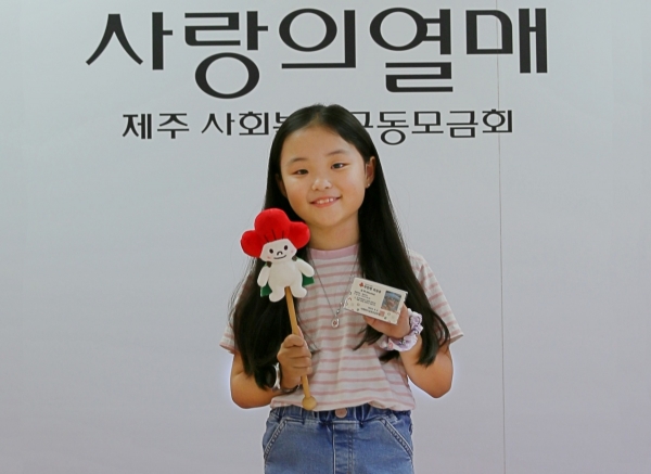 남광초등학교 김아람 학생이 착한펫 회원증을 들고 기념촬영을 하고 있다.